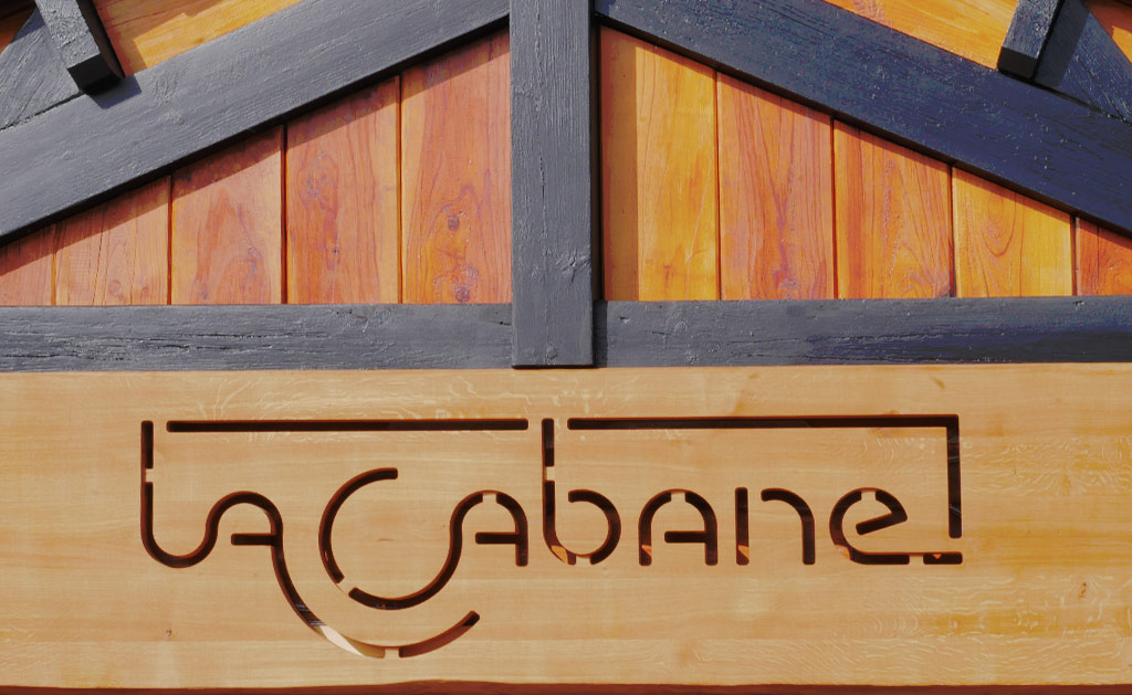 l'enseigne du restaurant, le logo apparaît sur une planche de bois via une découpe au laser.