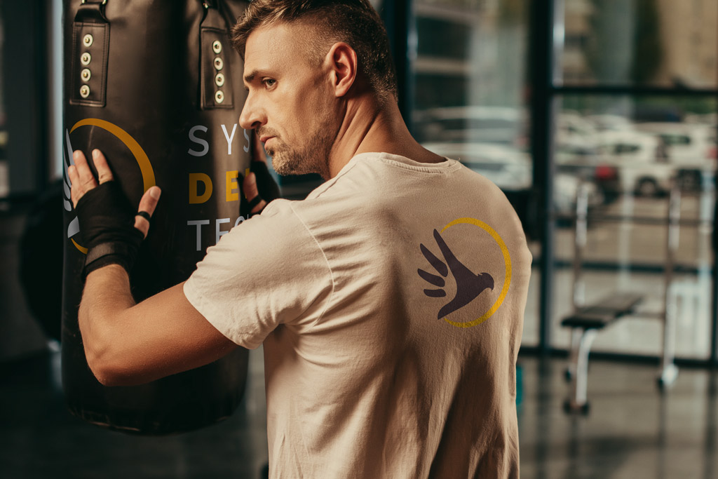 Mockup d'un homme à l'entrainement, devant un sac de frappe, avec un t-shirt floqué aux couleurs du club.